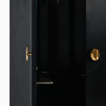 Black lacquered wood cabinet with brass pulls at Studio Schalling