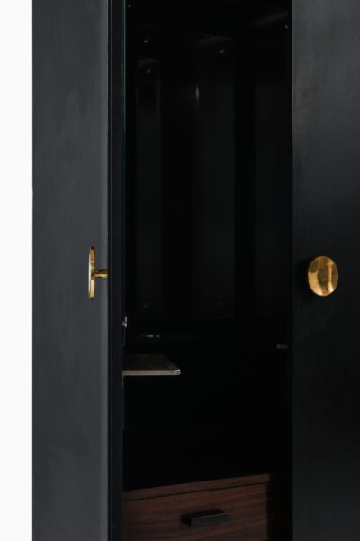 Black lacquered wood cabinet with brass pulls at Studio Schalling